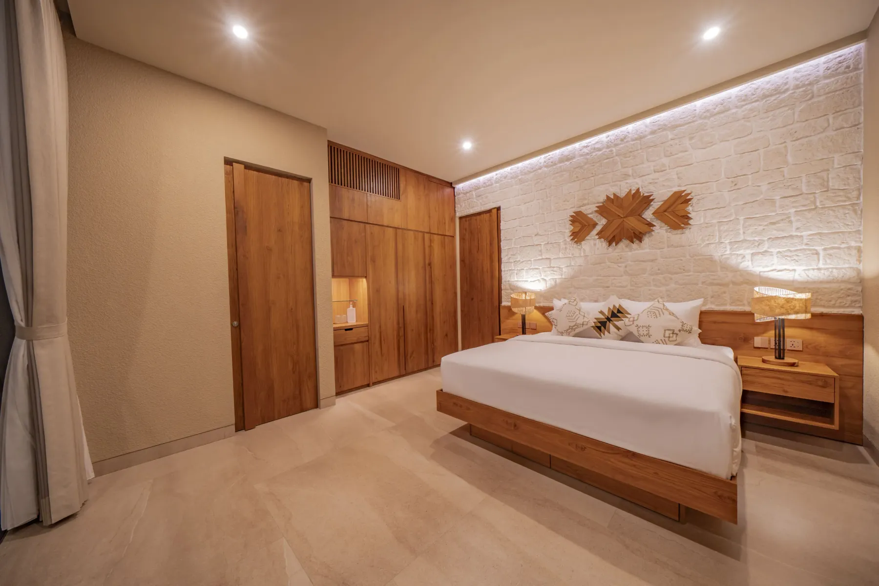Second bedroom with a timber wardrobe wall and brick headboard at Villa Navaho